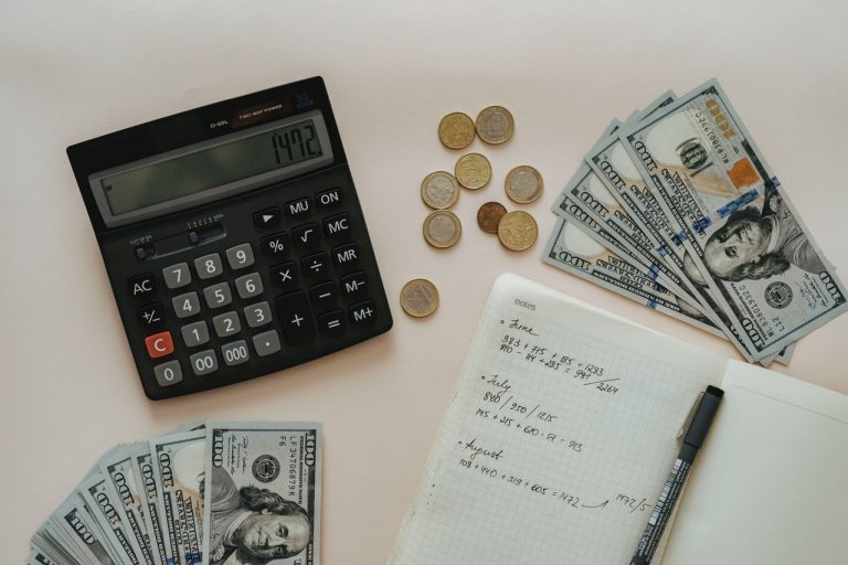 Black calculator beside coins and notebook