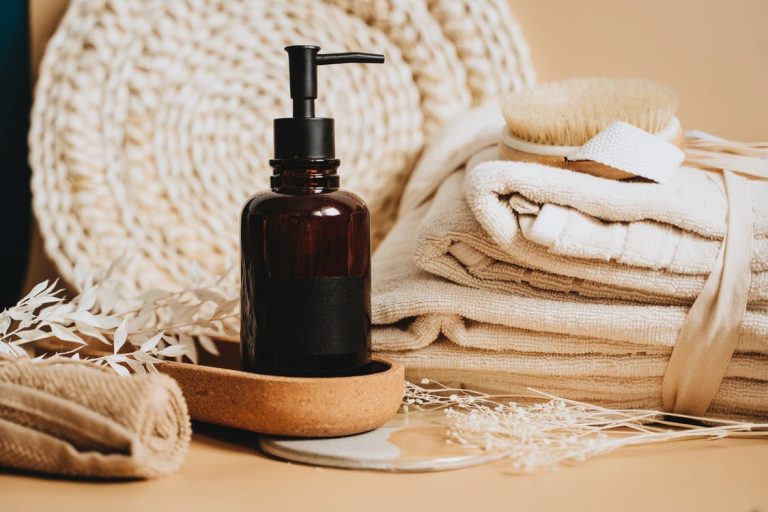 Body lotion glass bottle beside towels and a brush