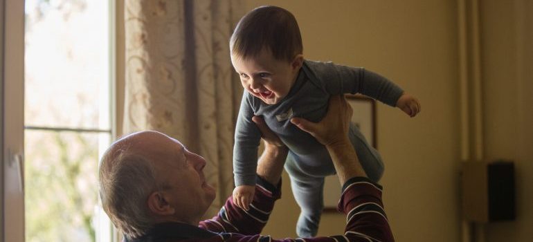 A senior holding his grandchild