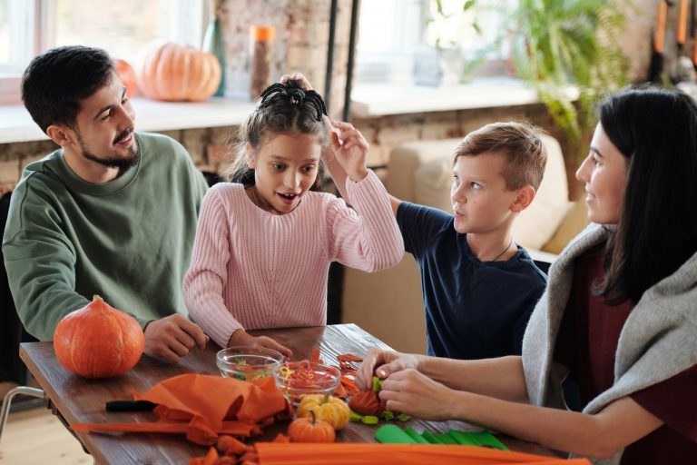 A family enjoying themselves while carving pumpkins which shows that Toronto fall with your family can be really fun.