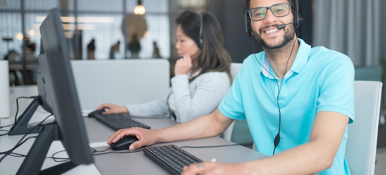 A person in an office smiling and using a laptop