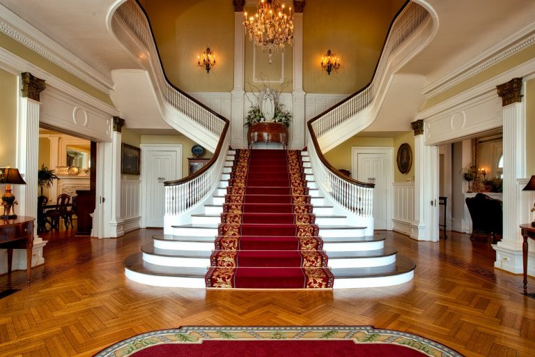 White marble staircase with red carpet.