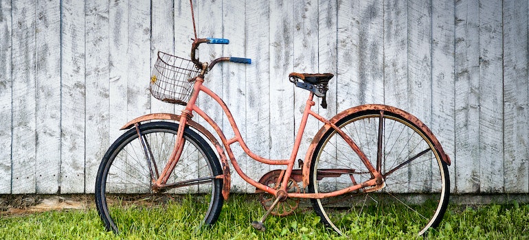 A red old bike leaned on the fence