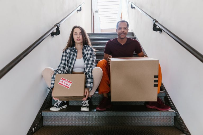 Man and woman sitting down holding cardboard boxes