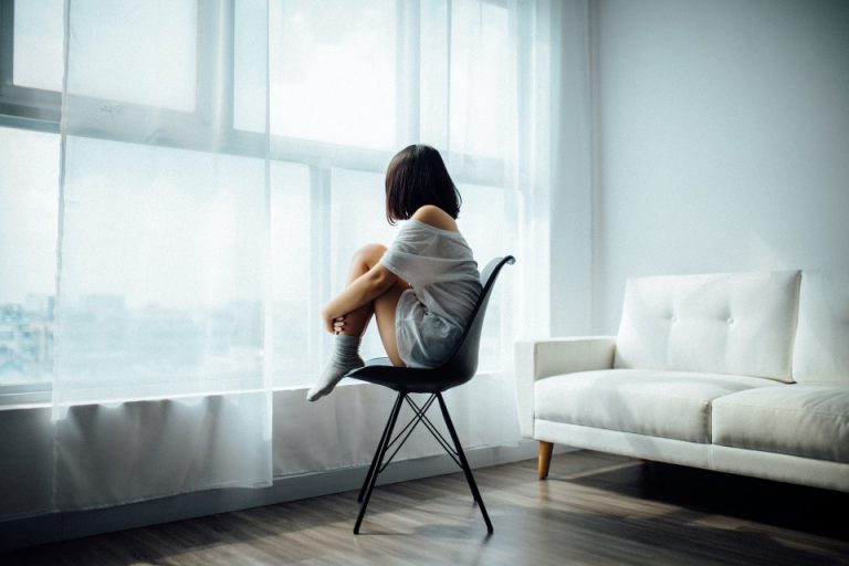 a woman sitting in a chair and thinking how to cope with moving depression after relocating to Canada