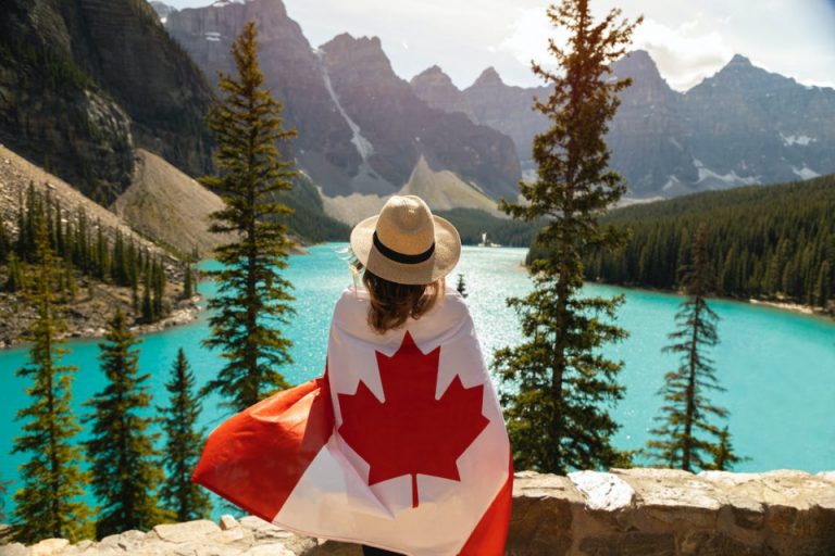 A woman with the Canadian flag standing by the lake