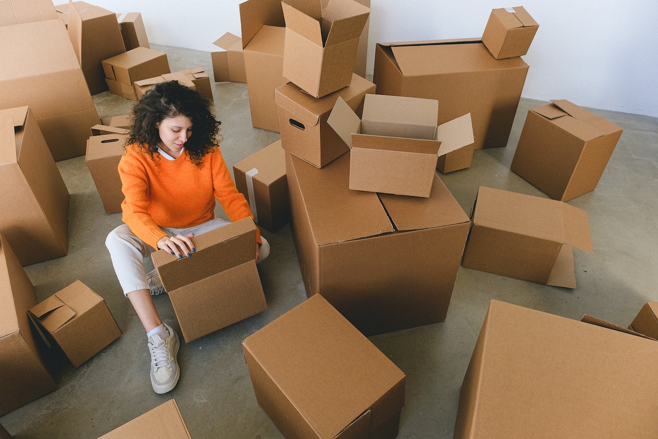 Woman surrounded by moving boxes, packing things