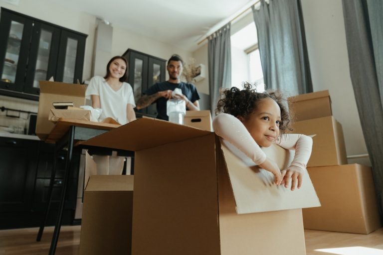 Little girl playing in a box while her parents are unpacking