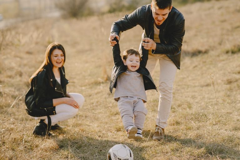 A mother and father playing outdoors with their daughter