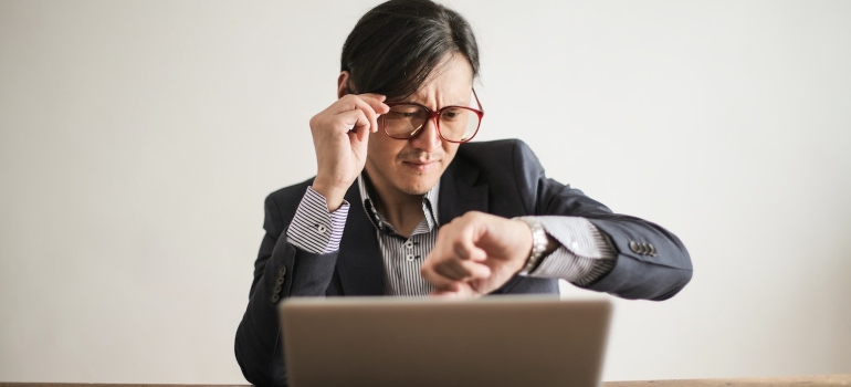 A person checking their watch and using a computer