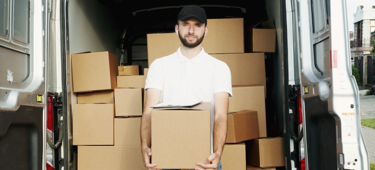 a man holding a box in front if a van