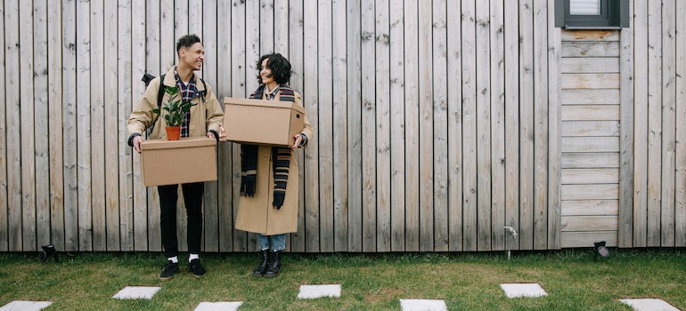 A couple with moving boxes in front of a new home, moved after understanding Toronto migration trends