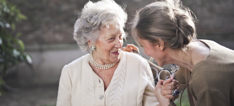 A mother and a daughter sitting on a bench and talking
