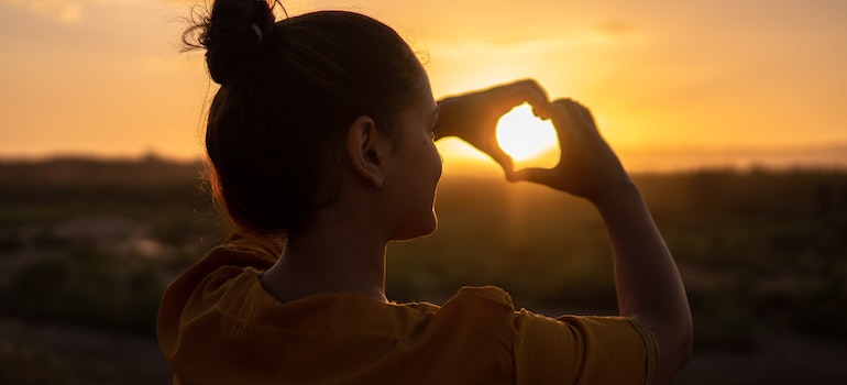 A woman in sunset making heart sign after deciding on living in Etobicoke