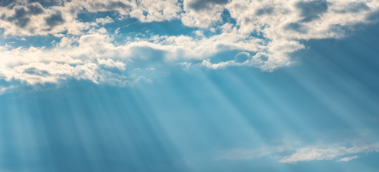 Sunrays shining through clouds on blue sky