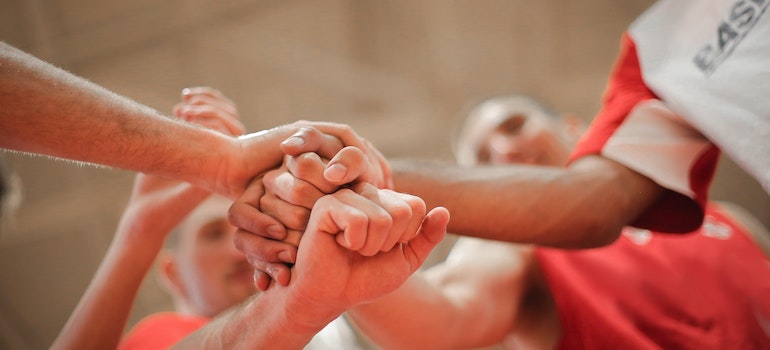 People joining hands on a sports event that is a great way to meet new people after moving to Oshawa