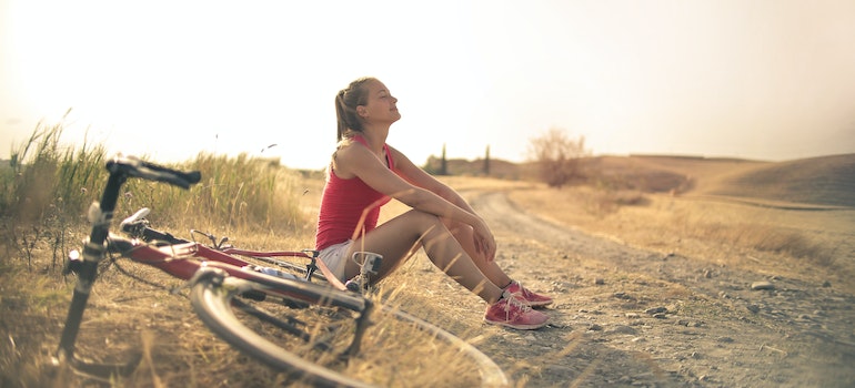 A woman taking a rest in nature with a bike next to her