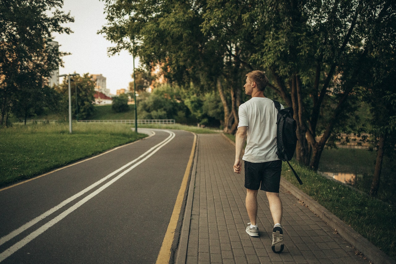 A man with a backpack walking down the long empty street after moving from Scarborough to Bradford