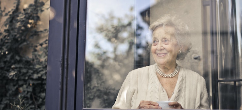 An elderly woman looking through the window