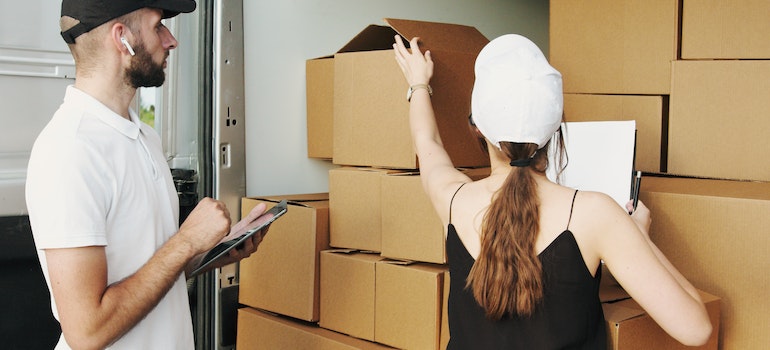 A man and a woman putting moving boxes into a truck