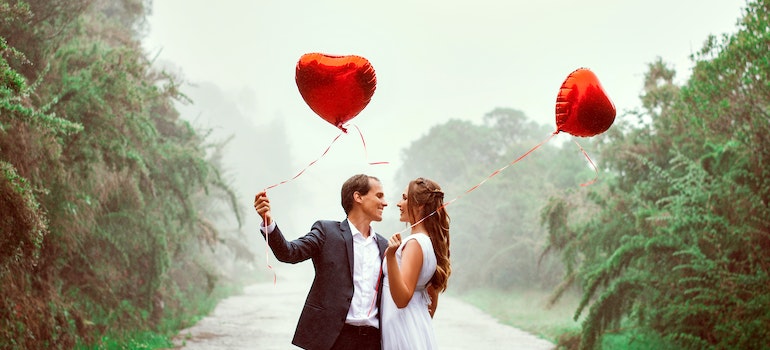 A couple holdong heart shaped balloons