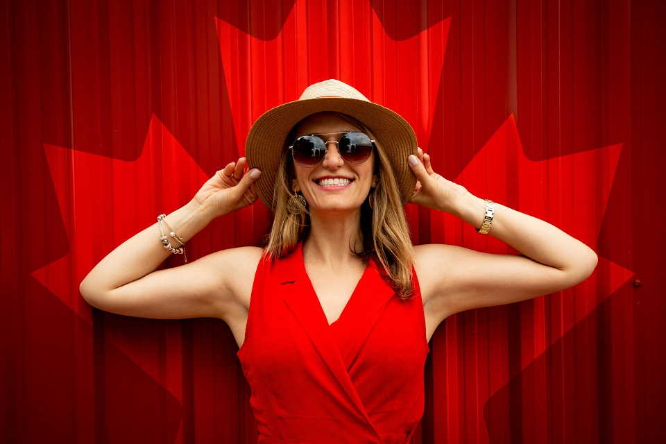 a girl smiling in front of a Canadian flag