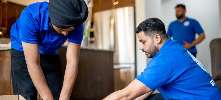 Two movers packing items inside a house for clients who are moving from Etobicoke to downtown Toronto