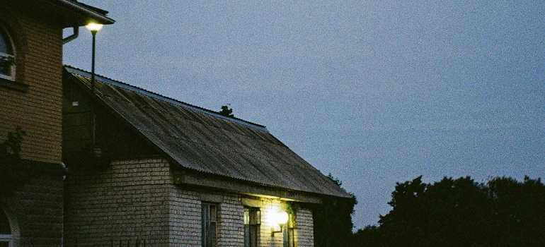 Old wooden house lit by a single lamp at night.