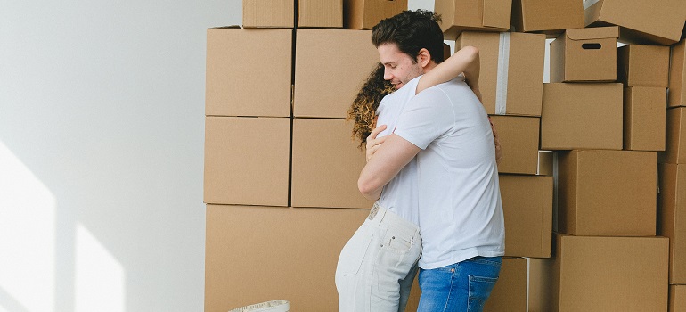 Couple embracing beside stacked moving boxes